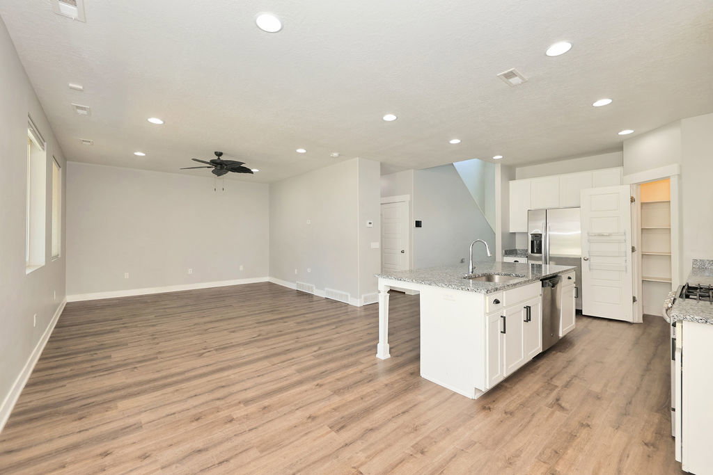 Open-concept living space featuring wood-finish flooring, recessed lighting, and a ceiling fan