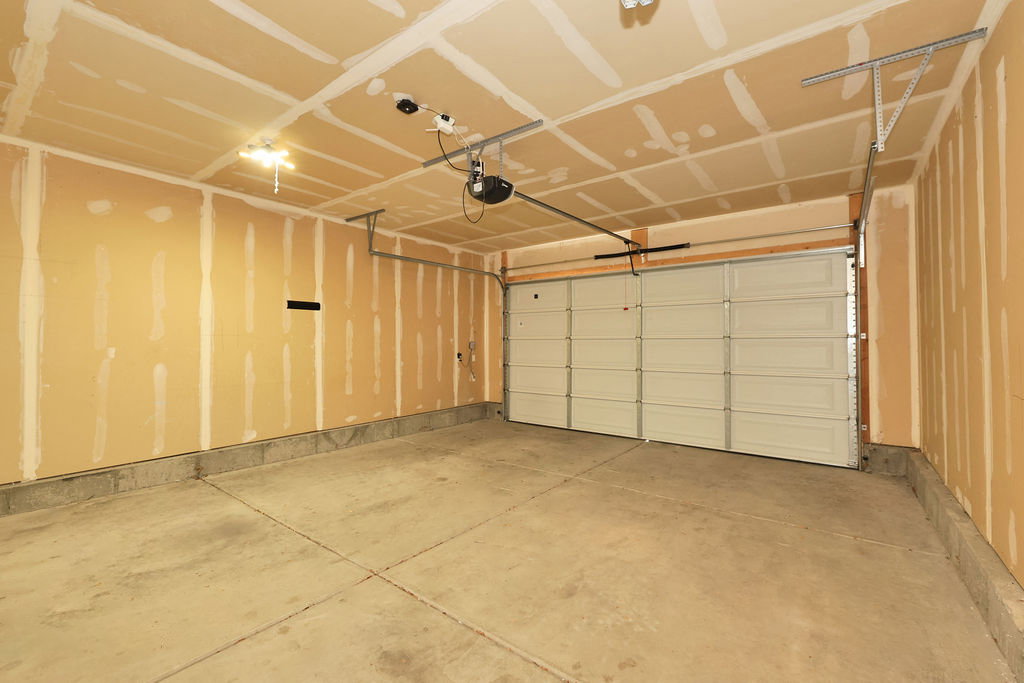 Spacious garage featuring a concrete floor, exposed drywall, and an overhead garage door with an automatic opener