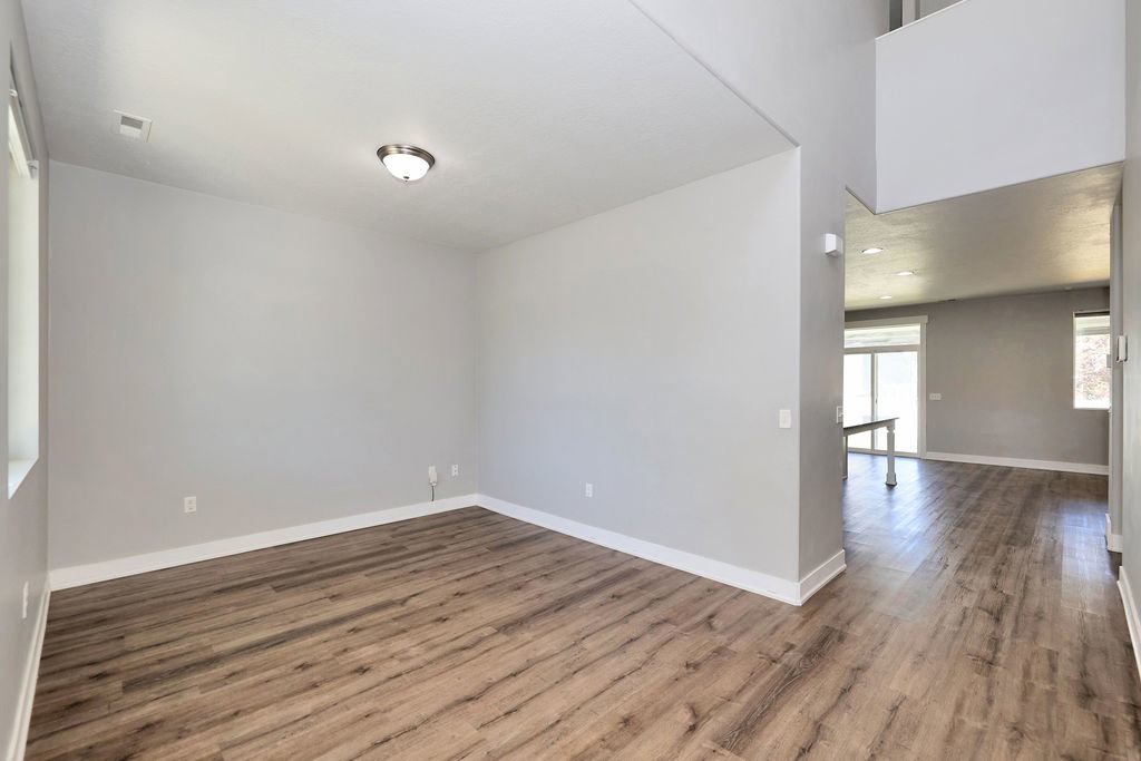 Spacious room featuring wood-finish flooring, light grey wall paint, and crisp white trim