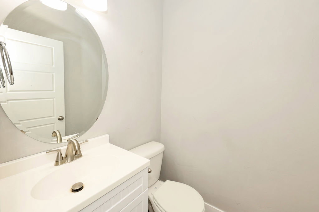 Bathroom vanity featuring a white cabinet with horizontal paneling, an integrated white sink, and a brushed nickel faucet