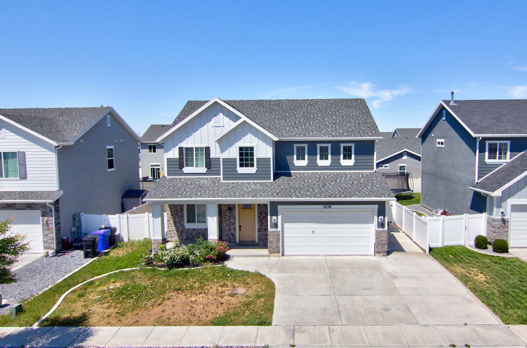 Contemporary two-story residence featuring a gray and white siding exterior with stone accents