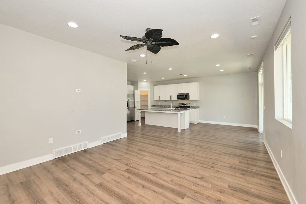 Open-concept living space featuring wood-finish flooring, recessed lighting, and a contemporary ceiling fan