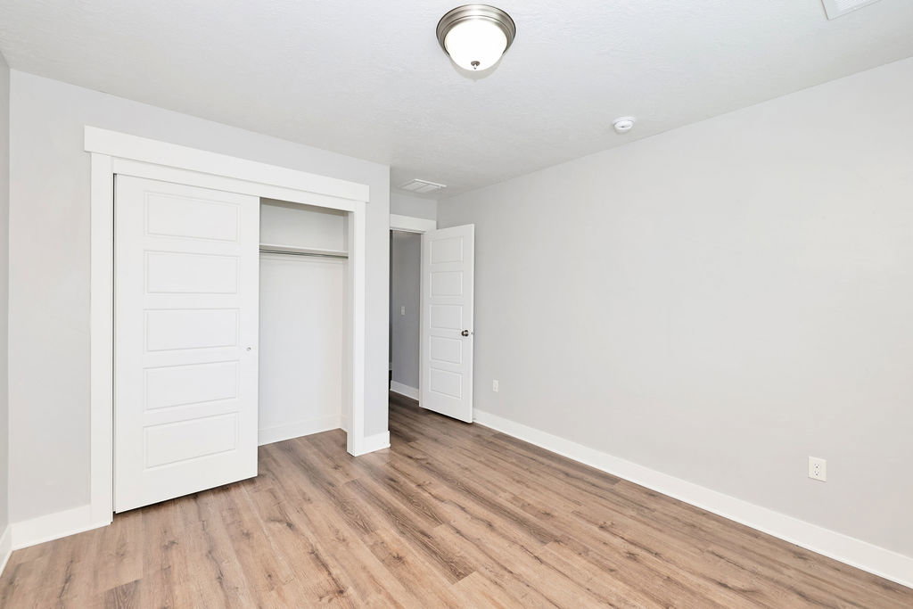 Room featuring wood-finish flooring, light gray wall paint, and white baseboards