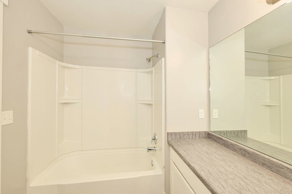 Bathtub and shower combination with integrated shelving, chrome fixtures, and a curved shower rod