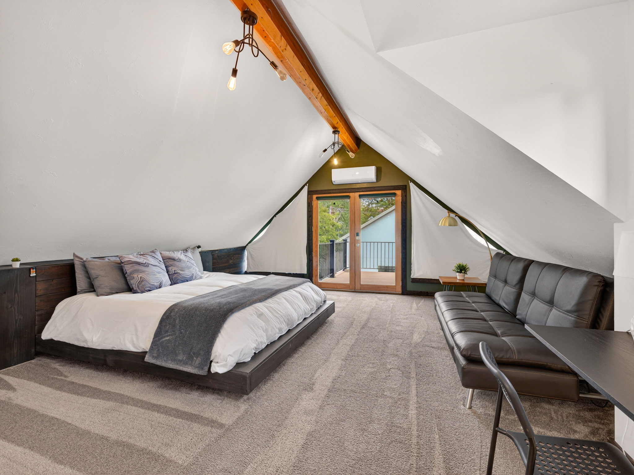 Attic conversion with exposed wooden beam, pitched white ceilings, and light grey carpet flooring