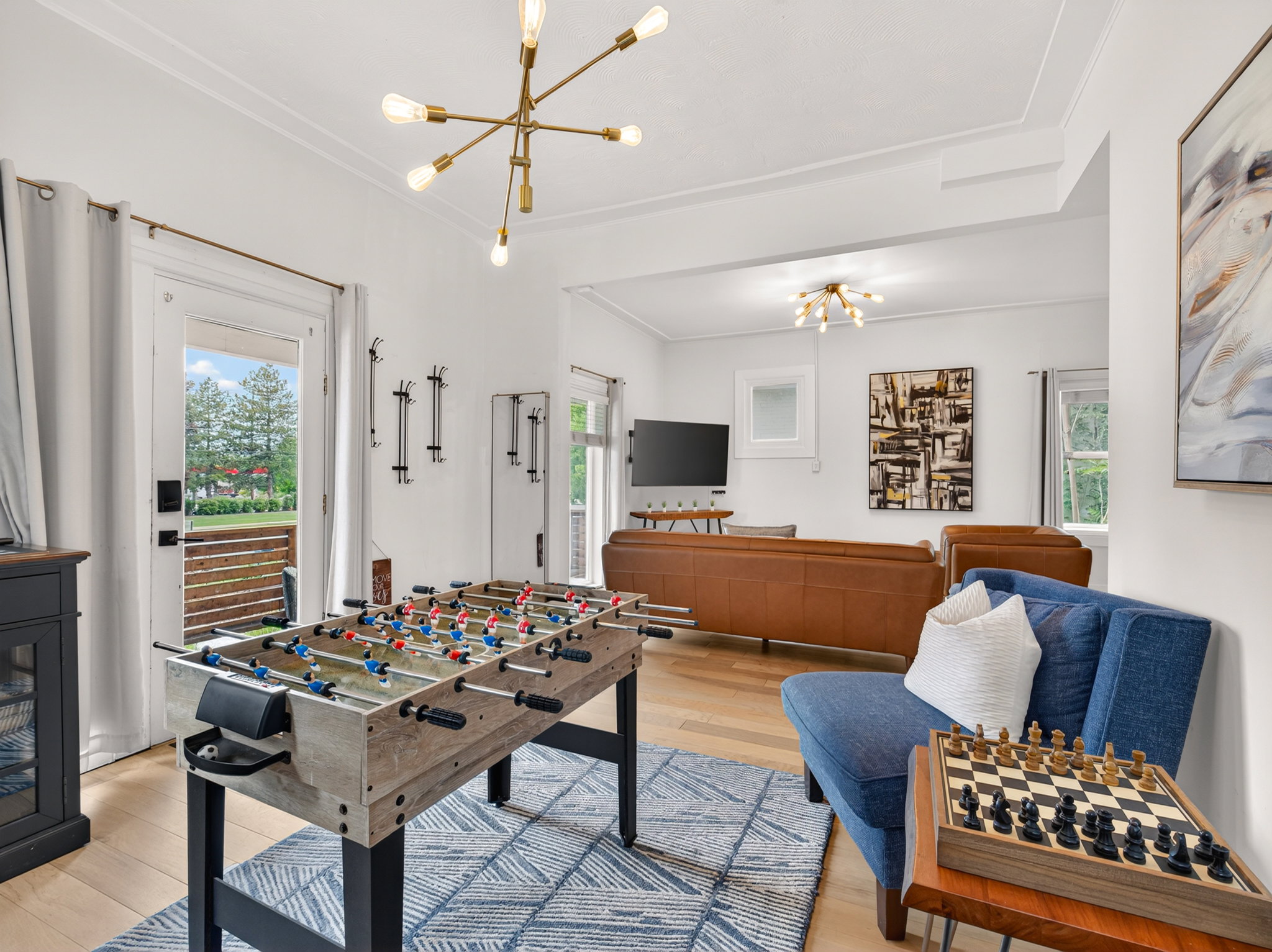 Bright interior space featuring light wood-finish flooring and a contemporary linear chandelier