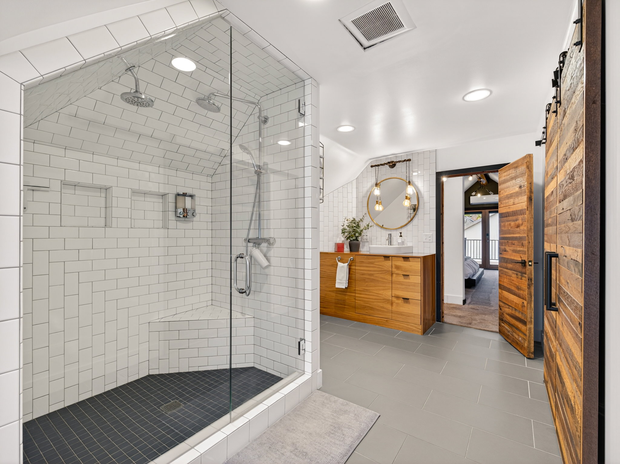 Spacious bathroom featuring a glass-enclosed shower with subway tile, dual shower heads, and built-in niches