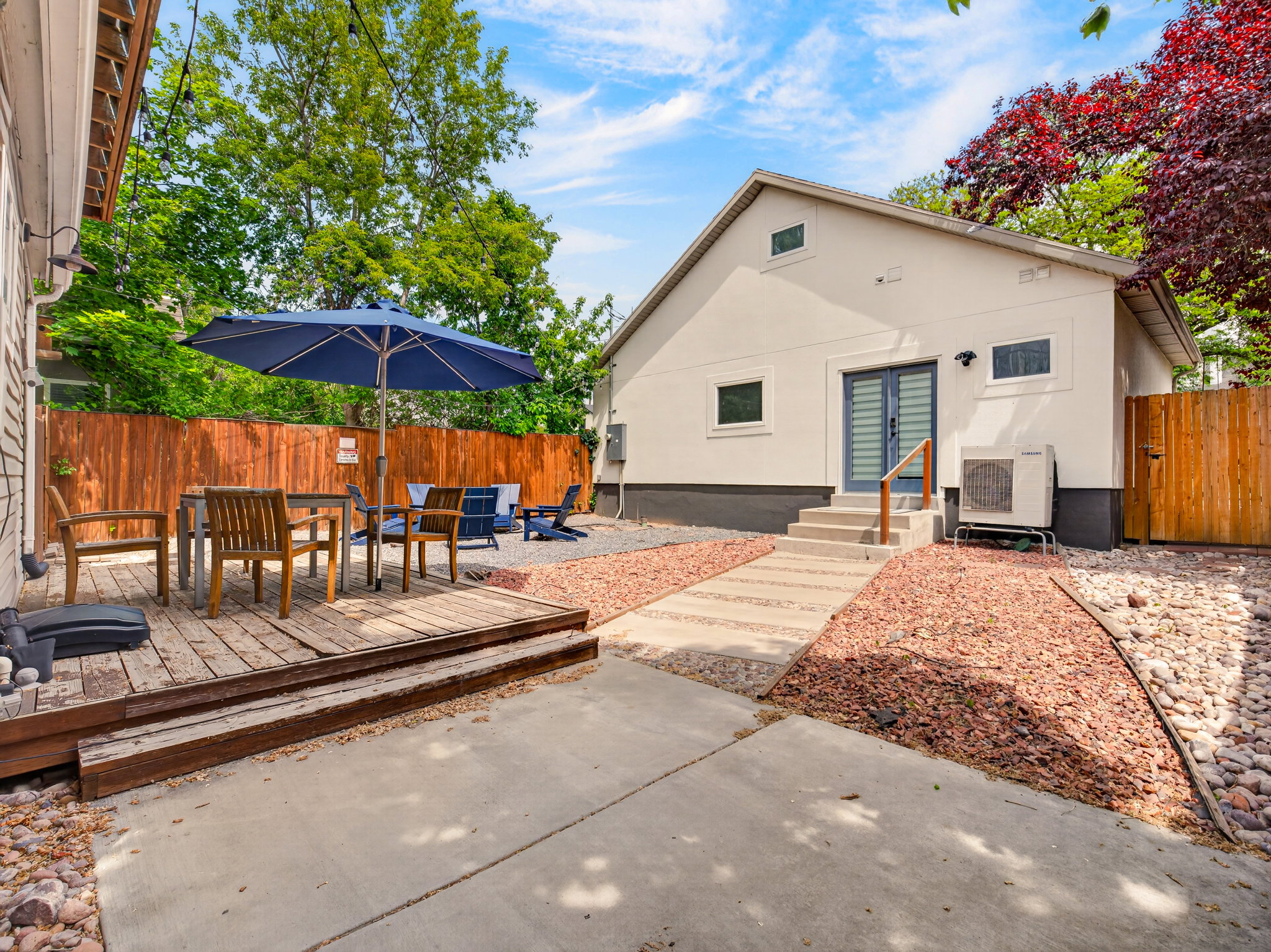 Backyard featuring a wooden deck, concrete patio, and gravel landscaping