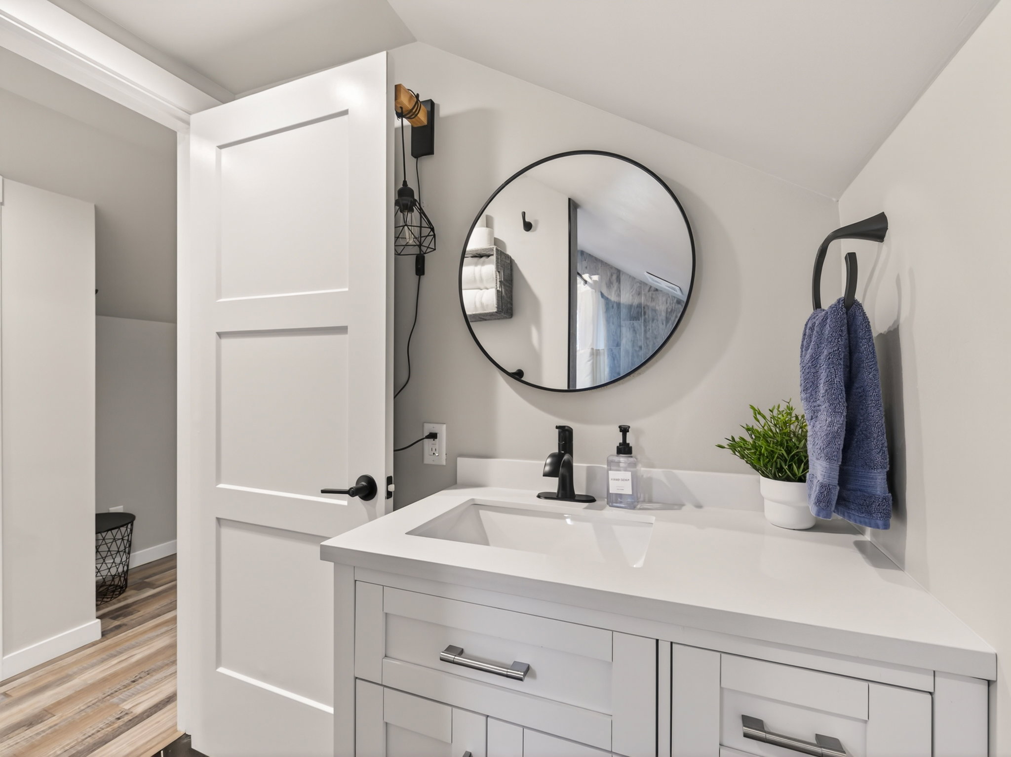 Vanity with an integrated rectangular sink, white countertop, matte black faucet, and wood-finish flooring