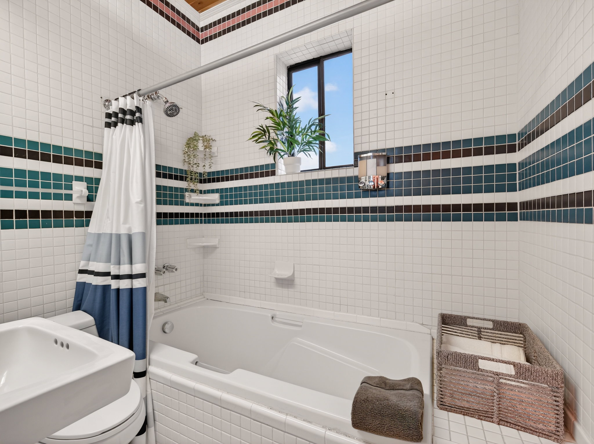 Bathroom featuring a tiled shower and soaking tub combination with an overhead window, white tile walls, and decorative accent bands