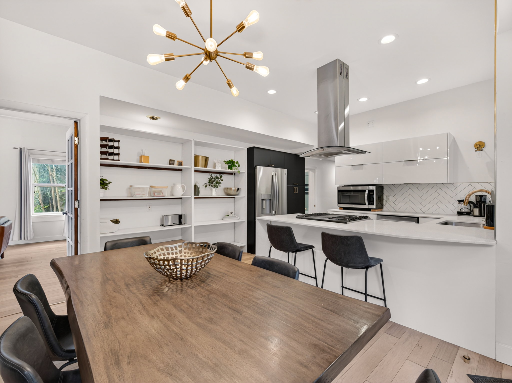 Open-concept kitchen and dining area featuring a large wood-finish dining table and light wood-finish flooring