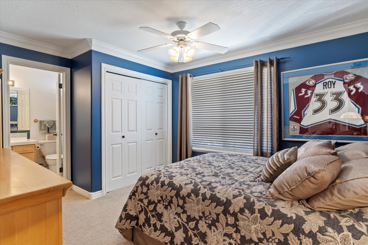 Bedroom featuring blue walls, white crown molding, and a ceiling fan with light fixture