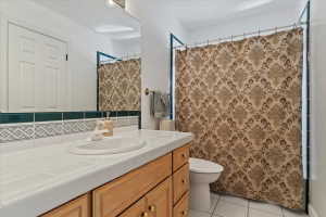 Bathroom featuring a built-in wood vanity with gold-tone hardware, a white tile countertop, and a drop-in sink