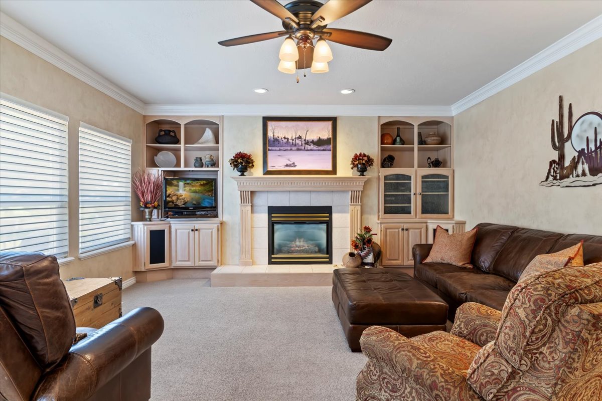 Living space featuring a central fireplace with a tile hearth and mantel, flanked by built-in cabinetry and shelving