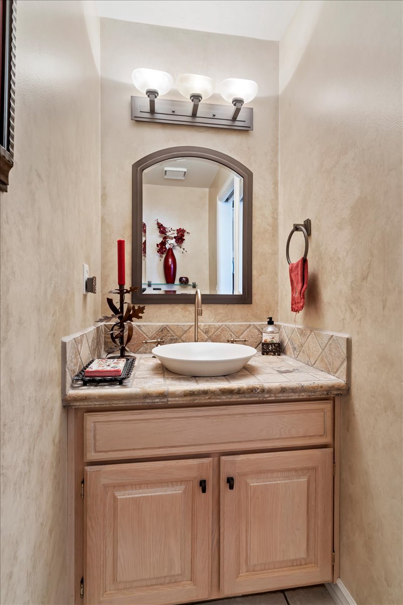 Vanity featuring a vessel sink, tile countertop, and tile backsplash