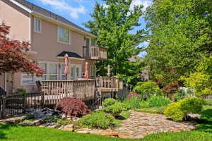 Rear exterior featuring a multi-level wood deck, a second-story balcony, and a manicured lawn