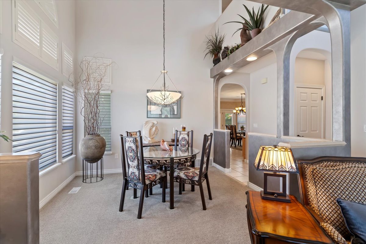 Formal dining area featuring vaulted ceilings, a contemporary chandelier, and large windows with plantation shutters