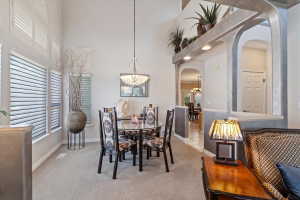 Formal dining area featuring vaulted ceilings, a contemporary chandelier, and large windows with plantation shutters