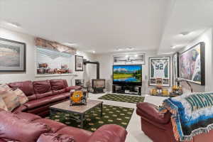 Spacious lower-level room featuring a wood-burning stove with a visible flue, recessed ceiling lighting, and a window with horizontal blinds