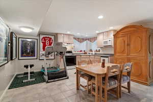 Well-appointed kitchen area featuring light wood cabinetry, dark countertops, and tile flooring