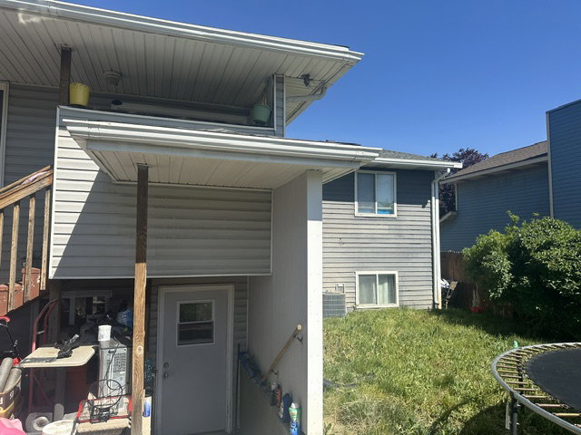 Vinyl siding exterior with a ground-level access door and a second-story balcony