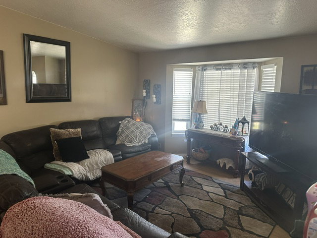 Living area with a prominent bay window featuring horizontal blinds