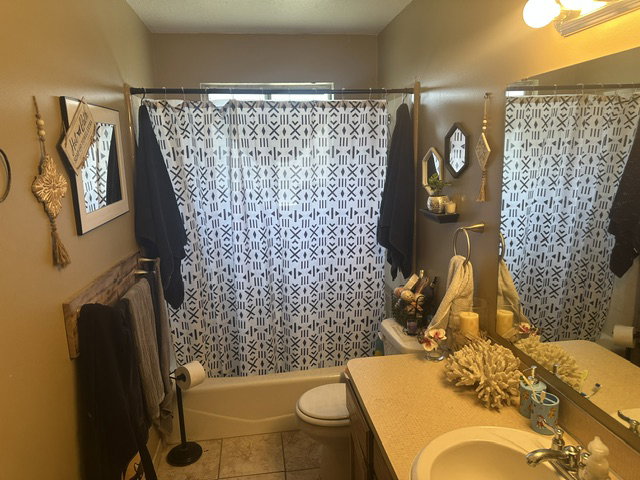 Bathroom featuring a built-in bathtub with shower, tiled flooring, an integrated vanity sink, and a large wall-mounted mirror