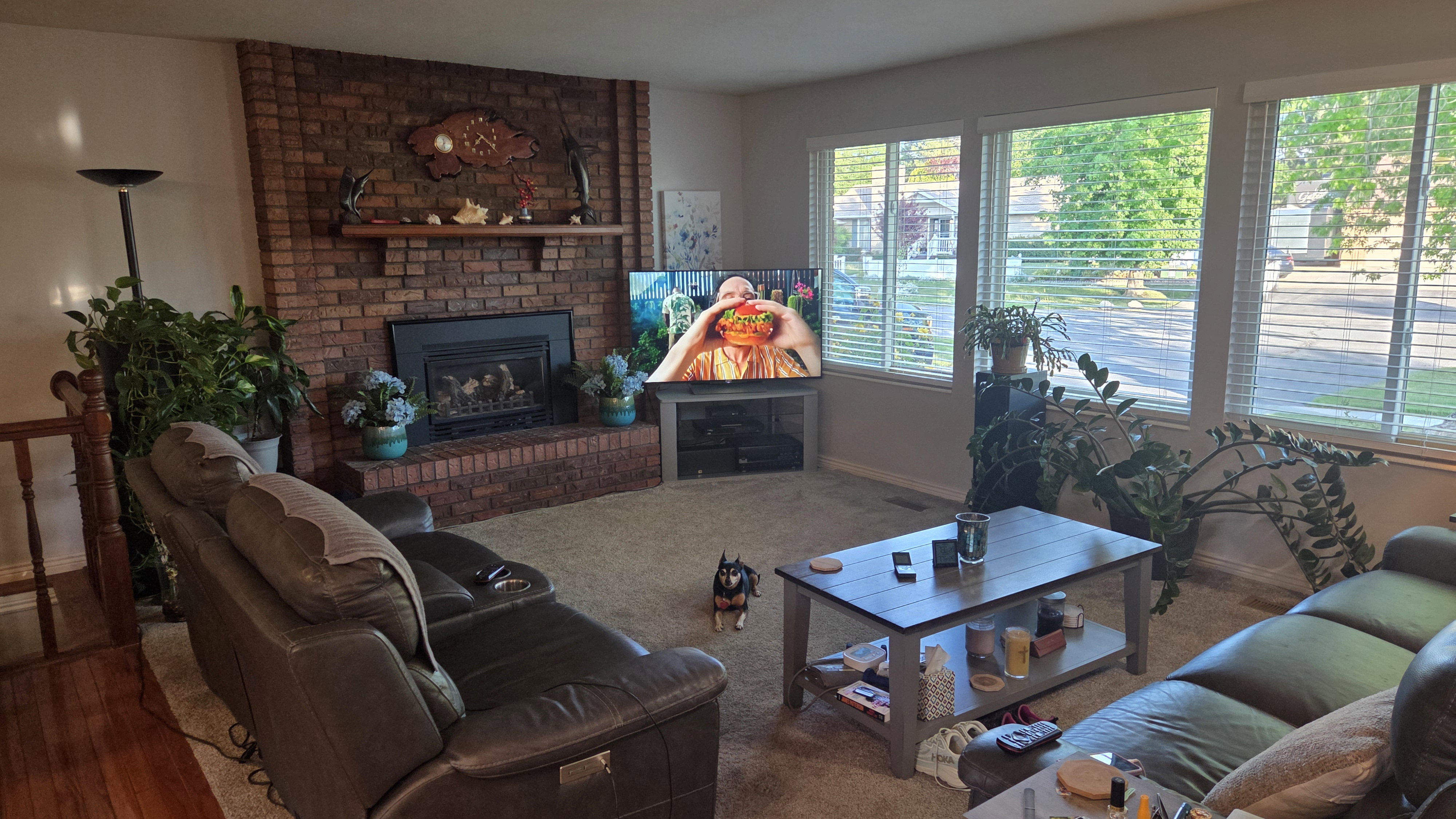 Living area featuring a floor-to-ceiling brick fireplace with a mantel, carpet flooring, a wall of multiple windows, and a built-in media console