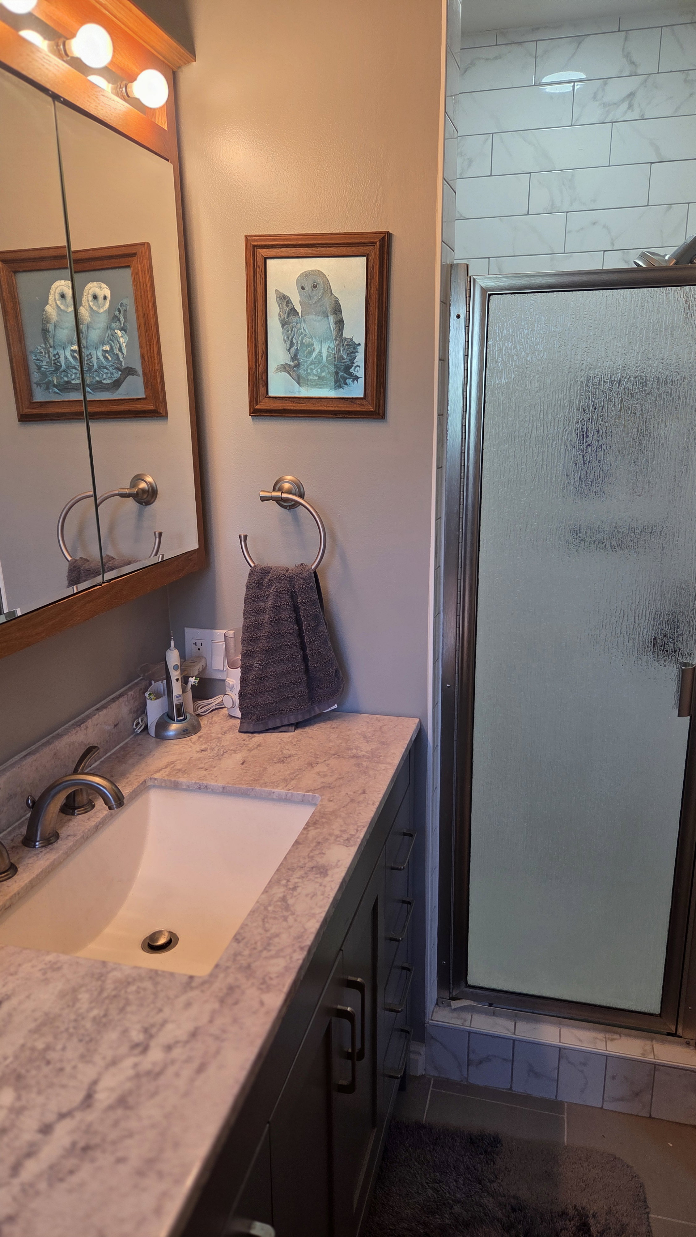 Bathroom featuring a dark wood vanity with a light-toned countertop, an undermount sink, and a framed mirror