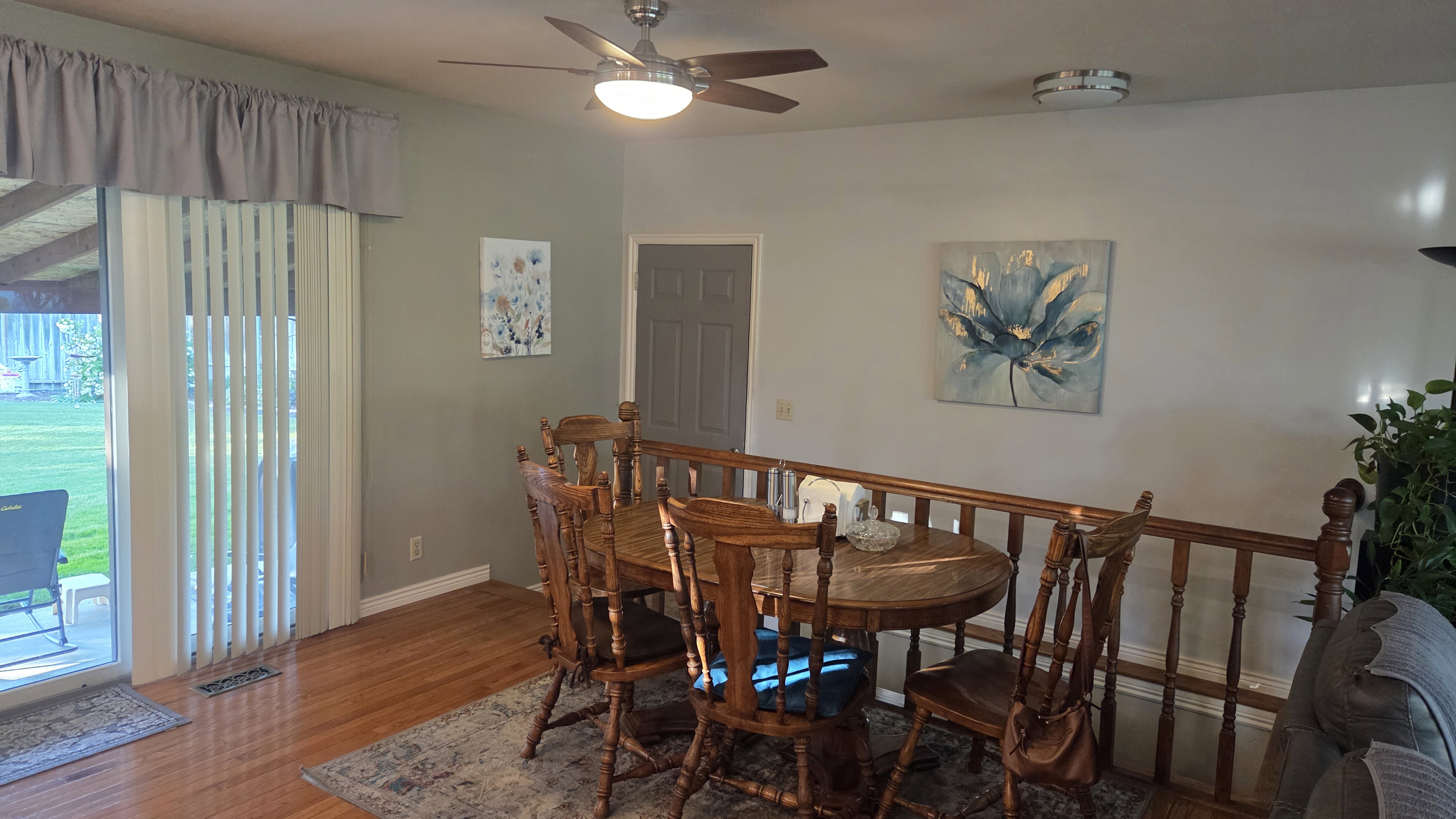 Dining area featuring wood-finish flooring, a ceiling fan with integrated lighting, and a wood railing overlooking a lower level