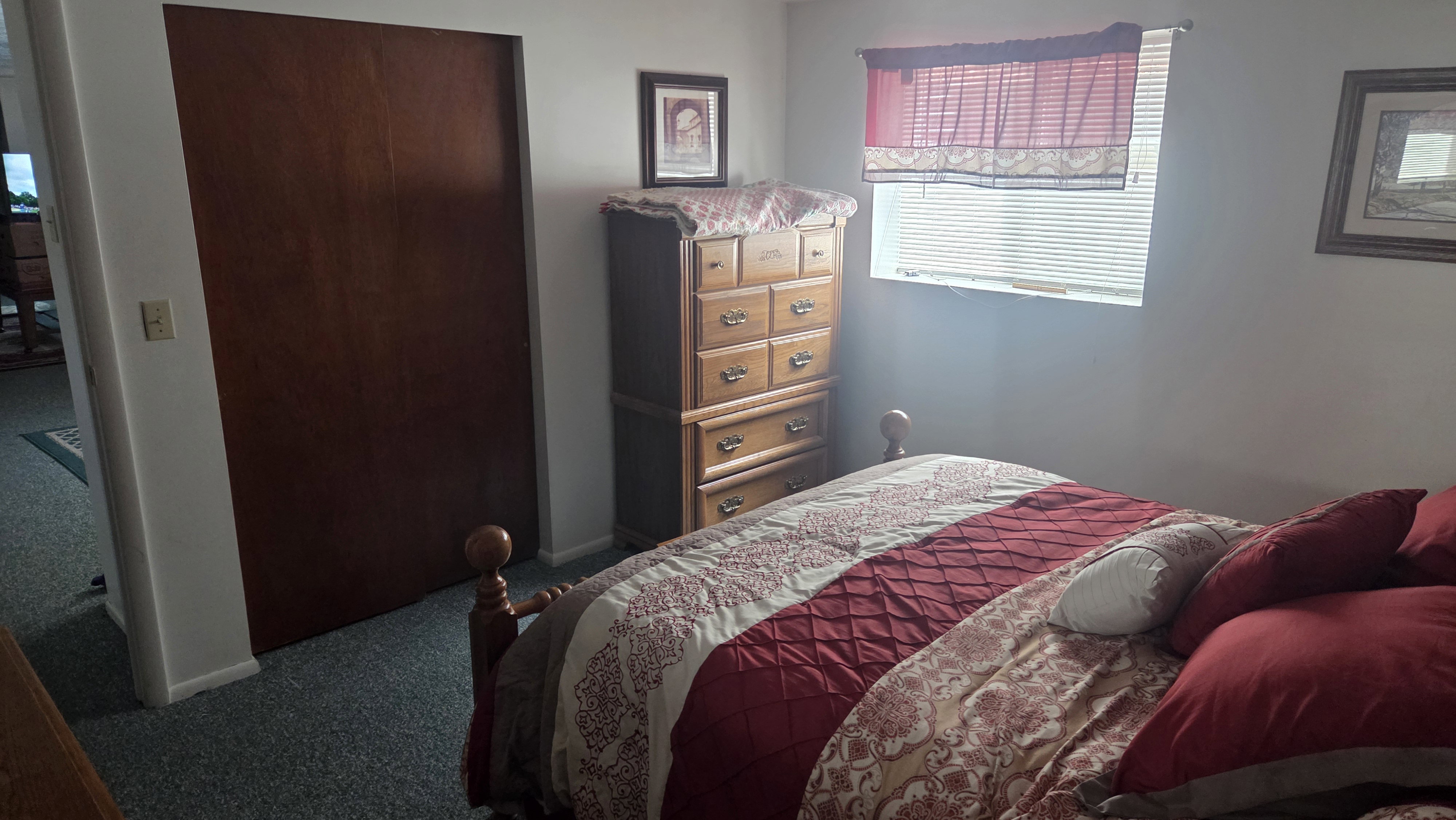 Interior room featuring a built-in wood-finish closet, window with horizontal blinds, and wall-to-wall carpeting