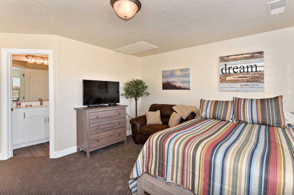 Carpeted bedroom featuring a light fixture, recessed ceiling vent, and neutral wall color