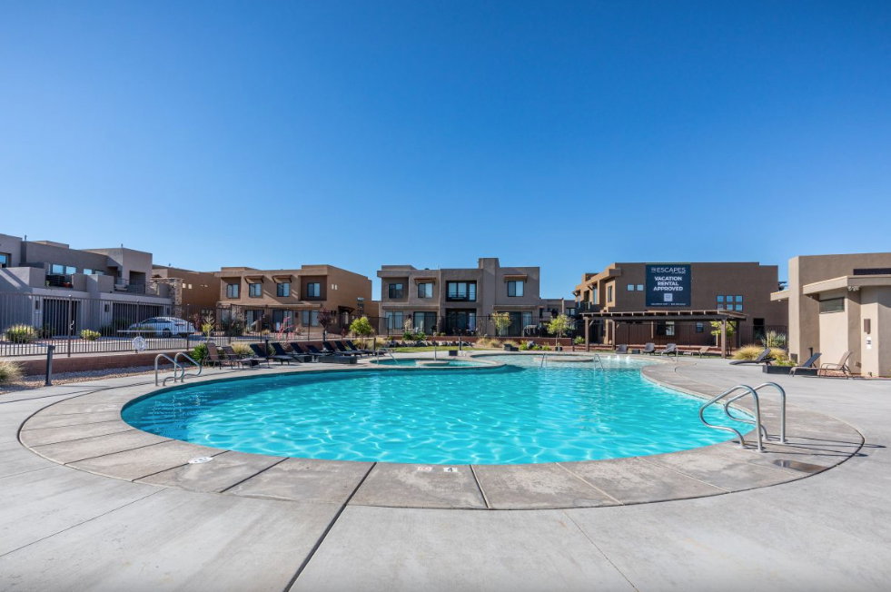 Resort-style swimming pool with integrated spa, surrounded by a concrete deck and a range of outdoor seating