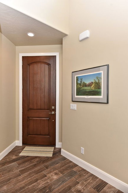 Entryway featuring a rich wood-finish door with an arched panel, diagonal wood-finish flooring, recessed lighting, and white baseboards