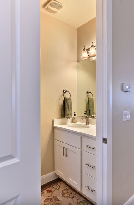 Powder room featuring a white vanity with brushed nickel hardware, a white countertop with an undermount sink, a wall-mounted mirror, and a two-light vanity fixture