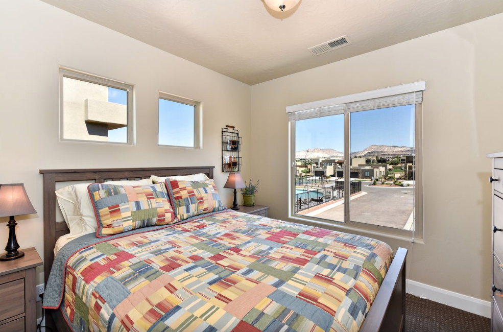 Bedroom featuring a large window with distant mountain scenery and a community pool