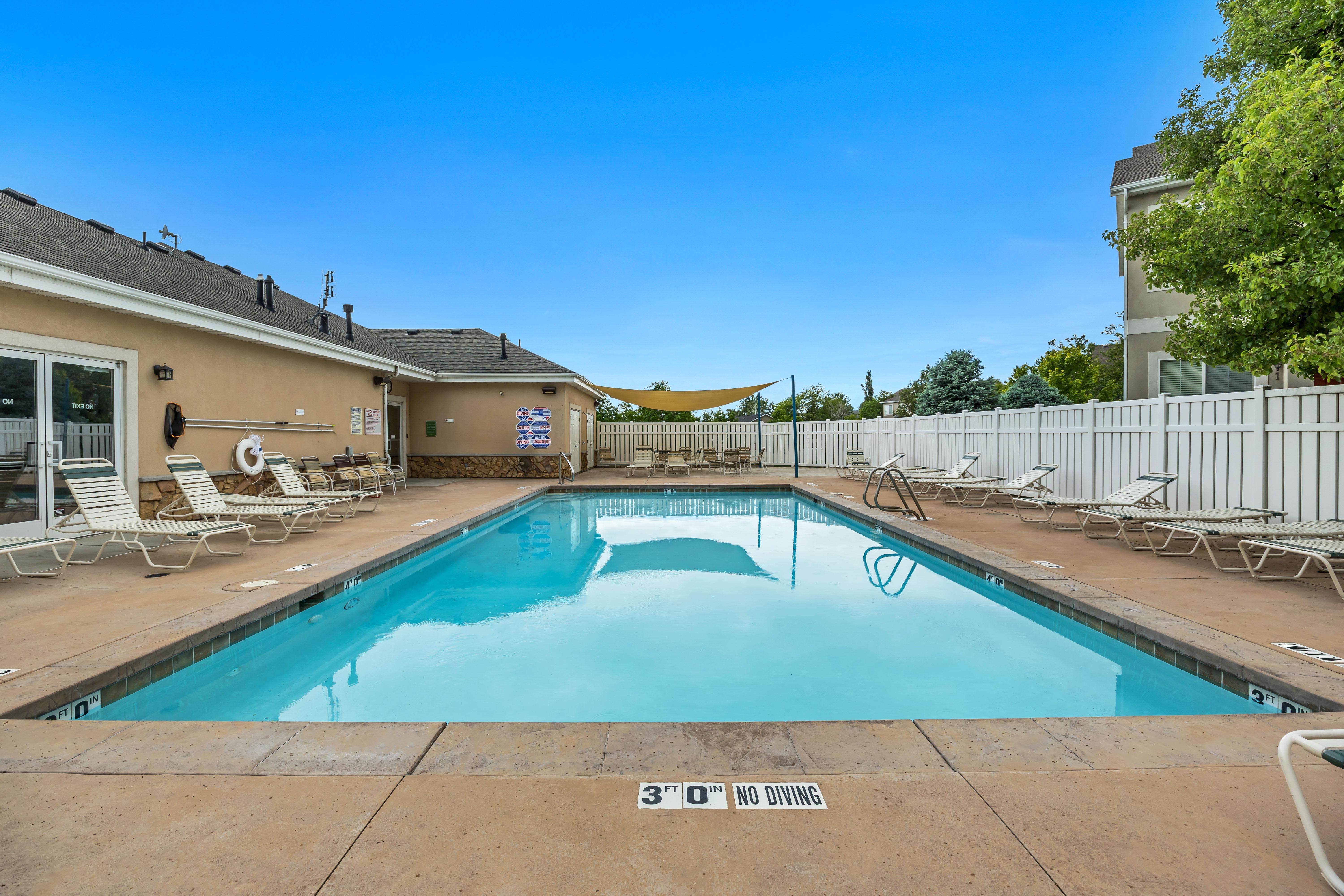 Outdoor in-ground swimming pool with lounge chairs.
