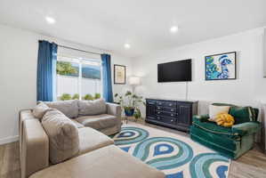Living area featuring wood-finish flooring, recessed lighting, and a large window with a distant mountain backdrop
