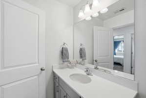 Bathroom vanity with a light countertop, integrated sink, and chrome faucet
