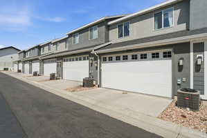 Row of townhomes featuring two-story facades with gray stucco and horizontal siding accents
