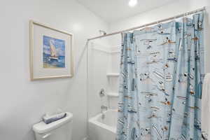White bathroom with a built-in tub/shower combination, polished chrome fixtures, and a recessed ceiling light