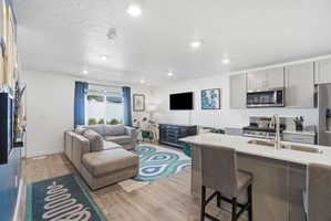 Open-concept living space featuring wood-finish flooring, recessed lighting, and a window with natural light