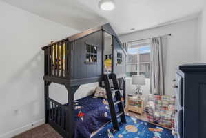 Charming bedroom featuring a window with natural light, neutral wall colors, and brown carpet flooring