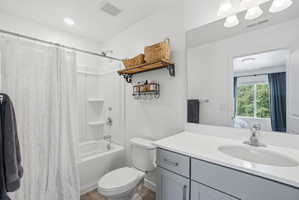 Bathroom featuring a white tub/shower combination, a vanity with a white countertop and gray cabinetry, a built-in sink, a large wall-mounted mirror, and wood-finish flooring