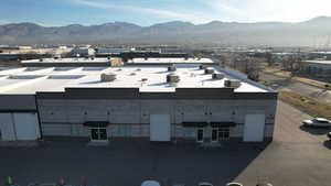 Commercial building featuring a flat roof, three roll-up doors, multiple entryways with awnings, and a partially brick facade