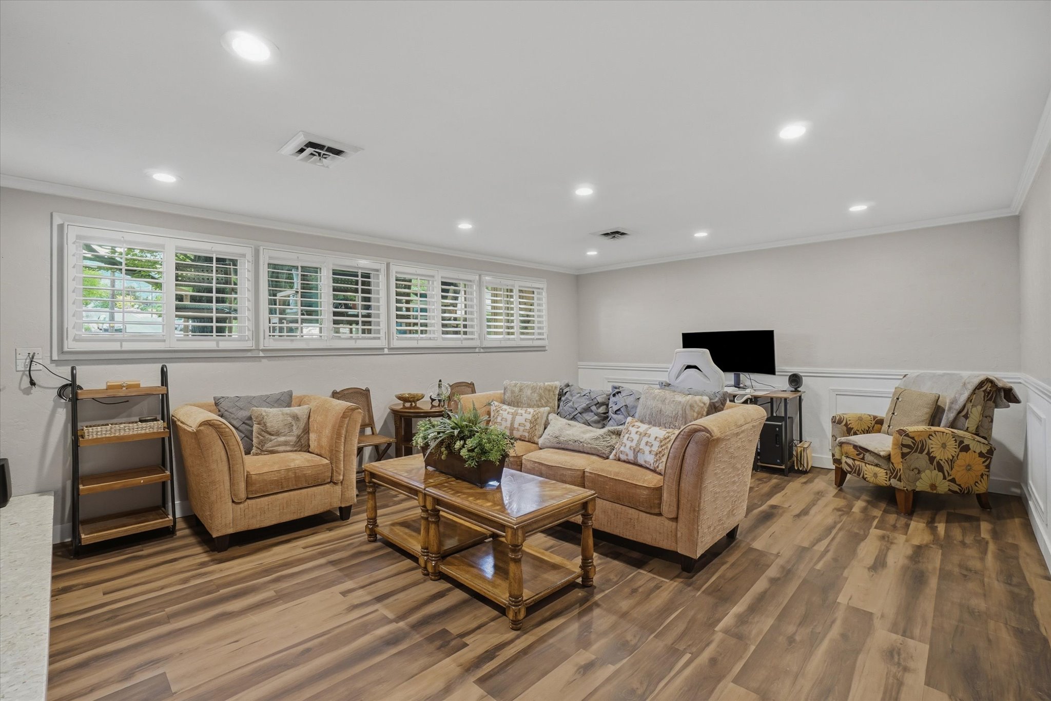 Spacious living area featuring wood-finish flooring, recessed lighting, and crown molding