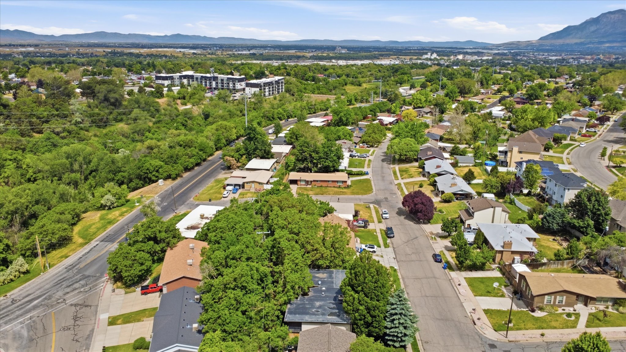 Aerial perspective showcasing a residential neighborhood with tree-lined streets and mountain backdrop