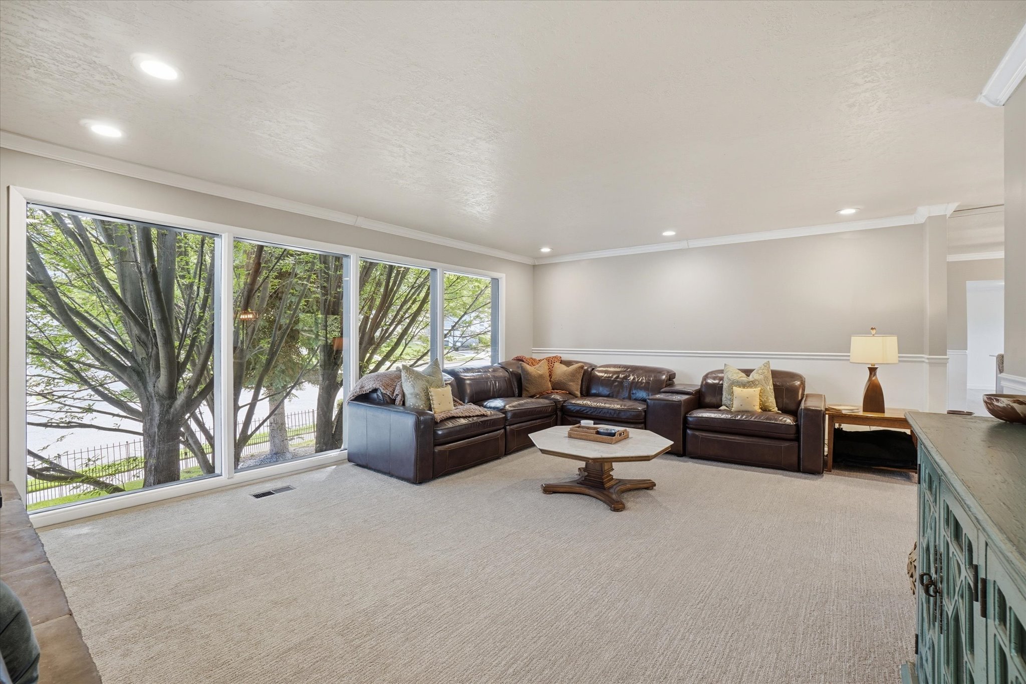 Living area featuring a wall of full-height windows, recessed lighting, crown molding, and neutral-toned wall paint