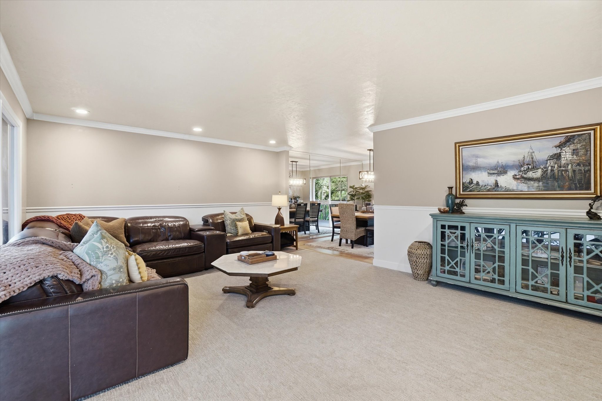 Spacious living area featuring neutral-toned walls, crown molding, recessed lighting, and light-colored carpeting