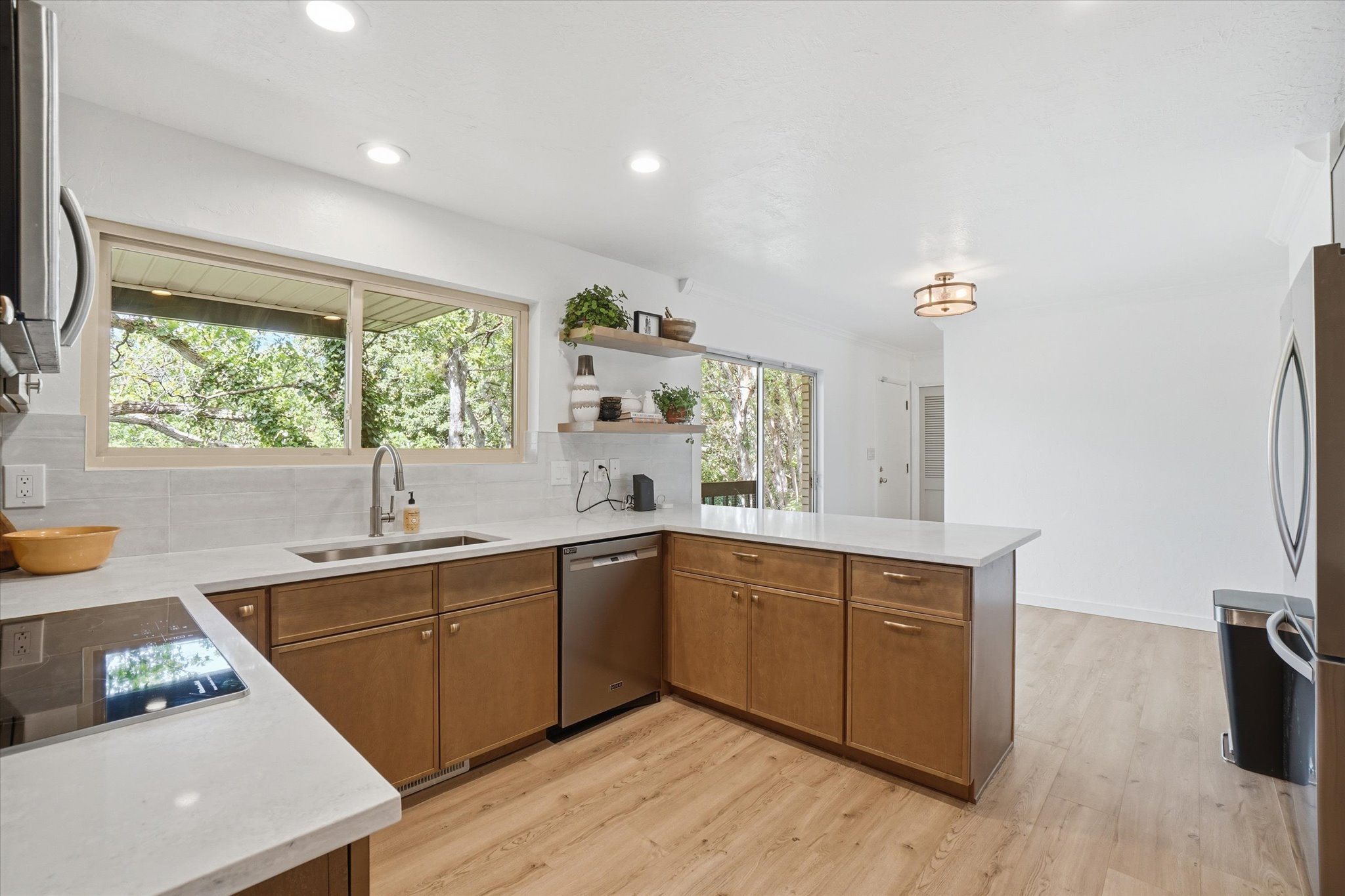 Kitchen featuring light wood-finish flooring and L-shaped cabinetry with stainless steel hardware